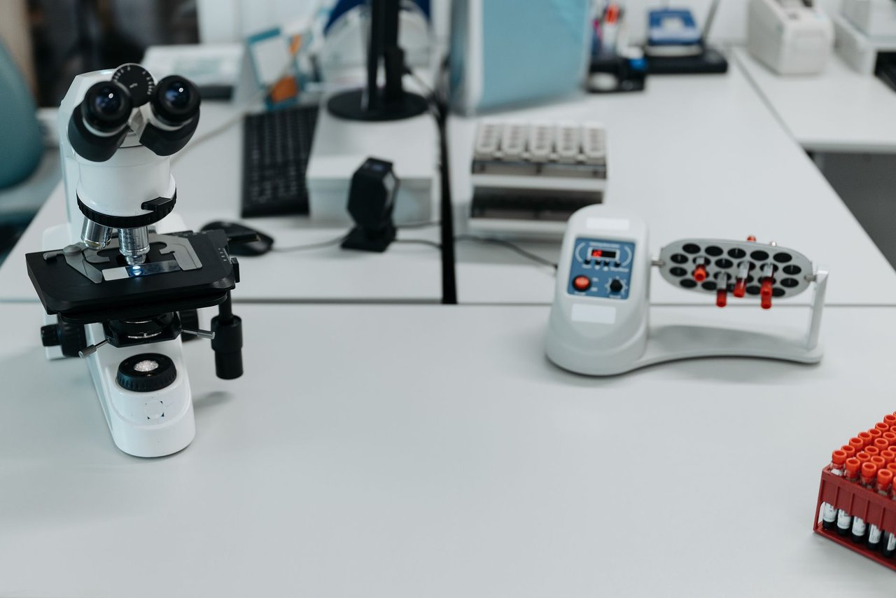 Microscópio e frascos dispostos em um laboratório equipado para análises científicas