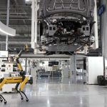 Cão-robô acompanha uma linha automatizada de montagem de veículos em uma fábrica de alta tecnologia.
