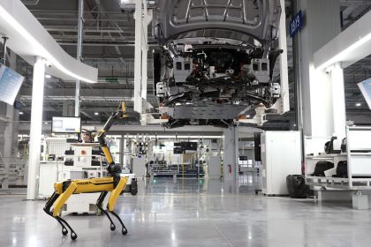 Cão-robô acompanha uma linha automatizada de montagem de veículos em uma fábrica de alta tecnologia.