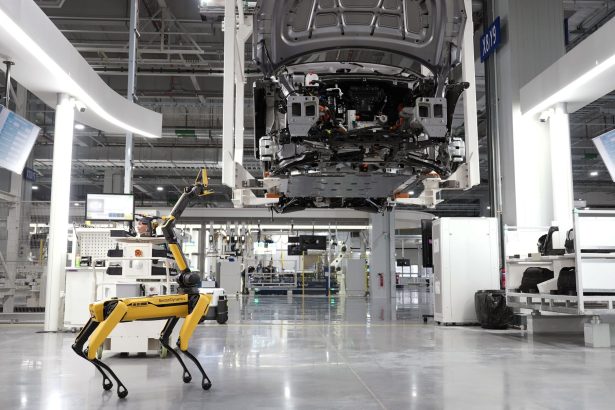 Cão-robô acompanha uma linha automatizada de montagem de veículos em uma fábrica de alta tecnologia.